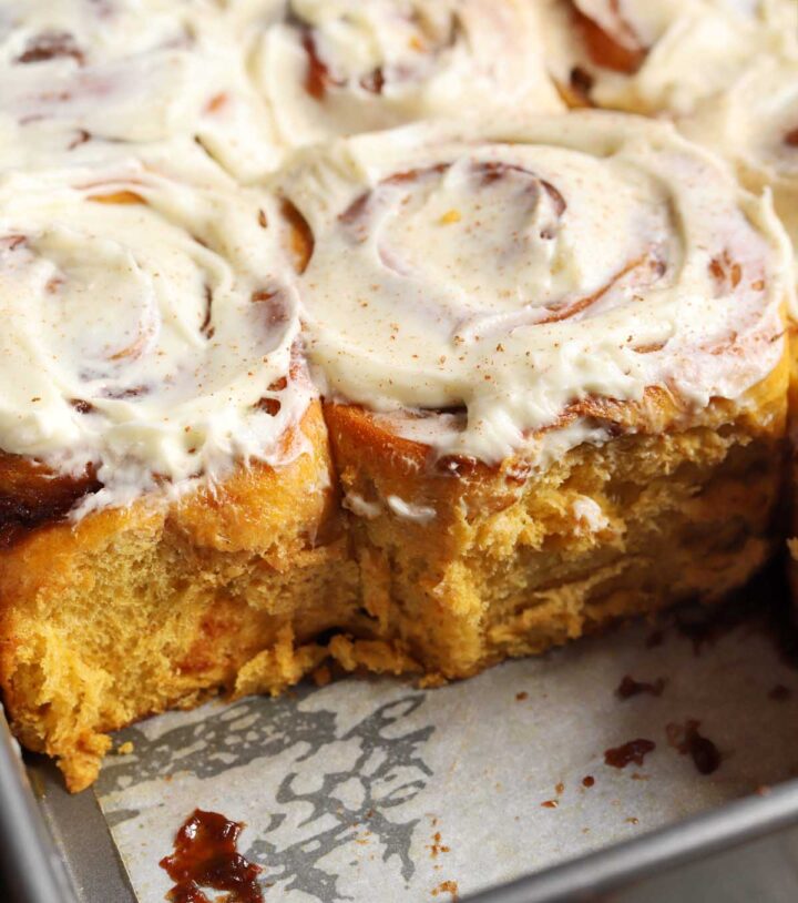best pumpkin cinnamon rolls in baking pan with cream cheese icing