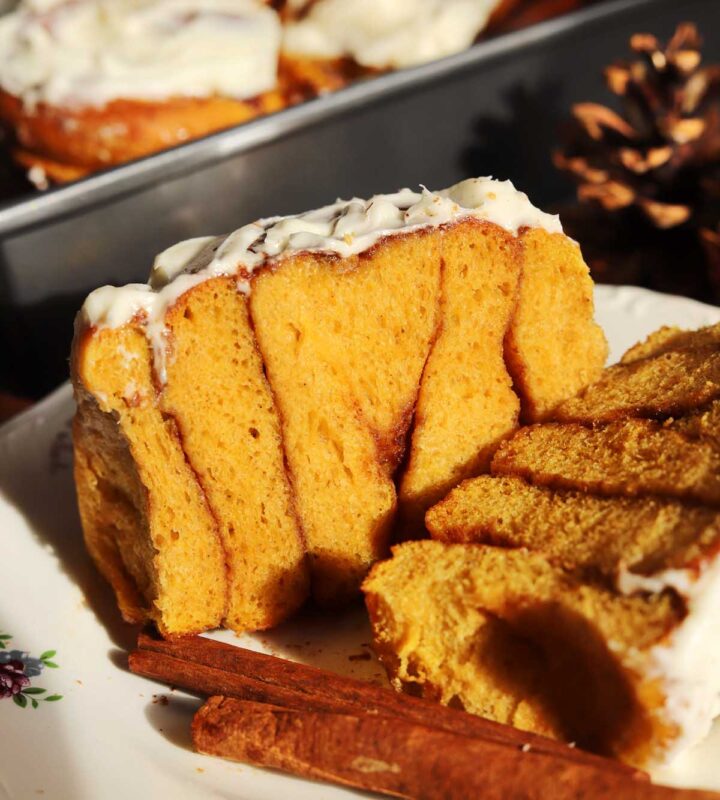 best pumpkin cinnamon roll sliced in half showing cross section on a plate