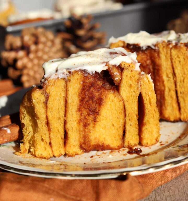 best pumpkin cinnamon roll sliced in half showing cross section on a plate
