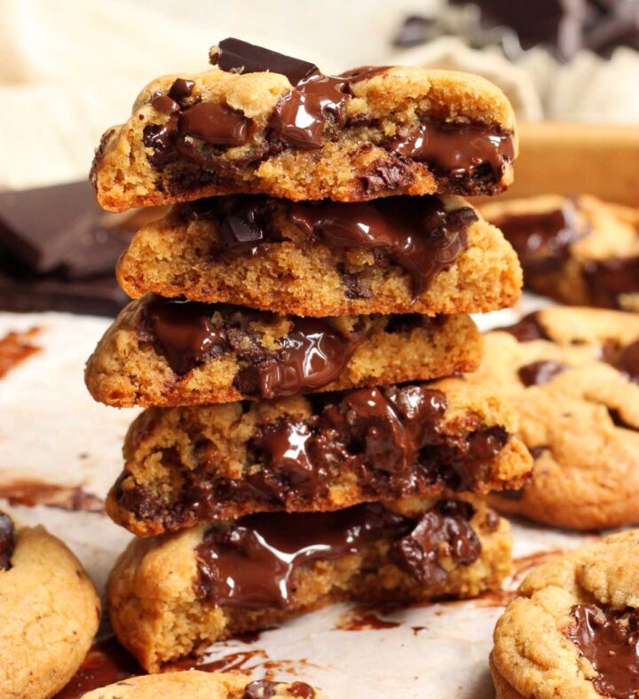 thick brown butter chocolate chunk cookies stacked up on baking sheet broken in half showing soft texture