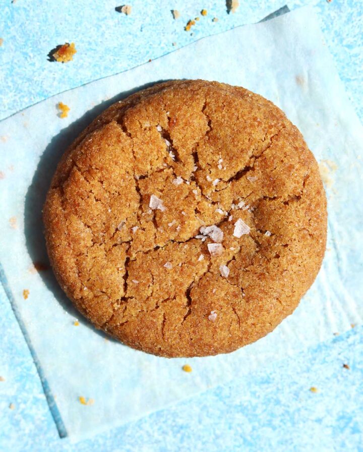 salted maple brown butter pumpkin cookie on piece of parchment paper with flaky salt