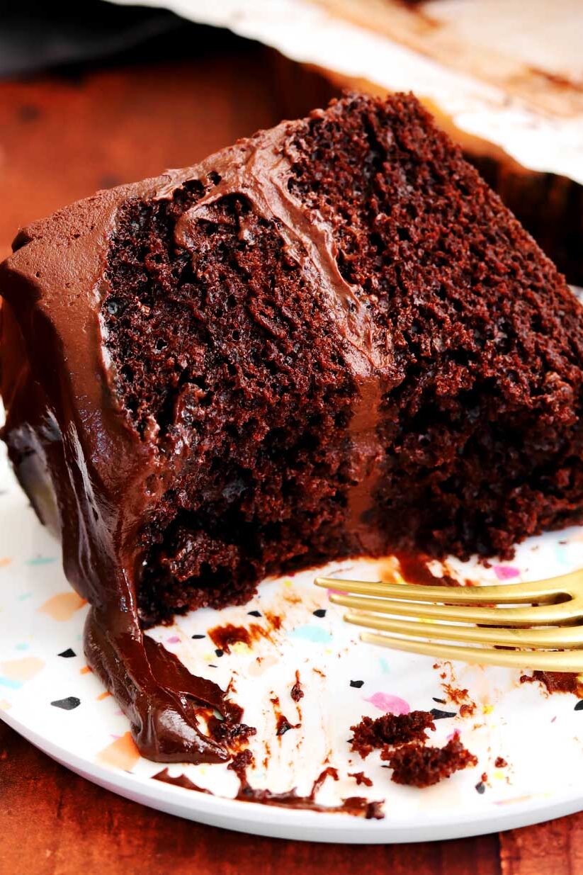 slice of best moist chocolate cake on a plate with fork and bite