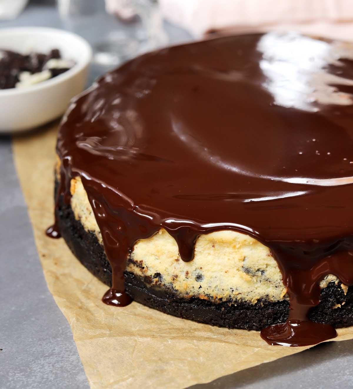 Oreo cookies & cream cheesecake before slicing with glossy chocolate ganache on top