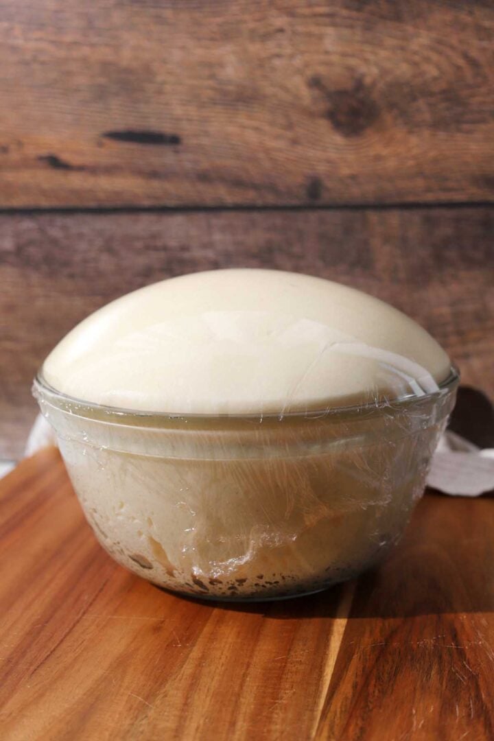 homemade dinner roll dough after bulk fermentation rising in glass bowl