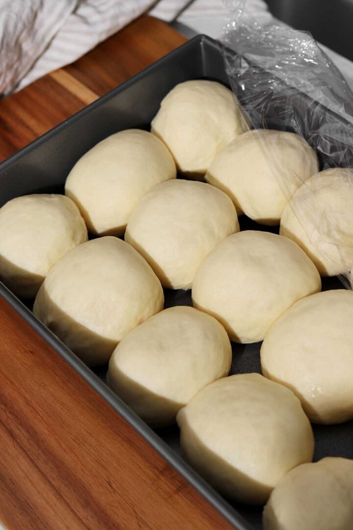 angle view of homemade dinner rolls dough balls in baking pan after proofing