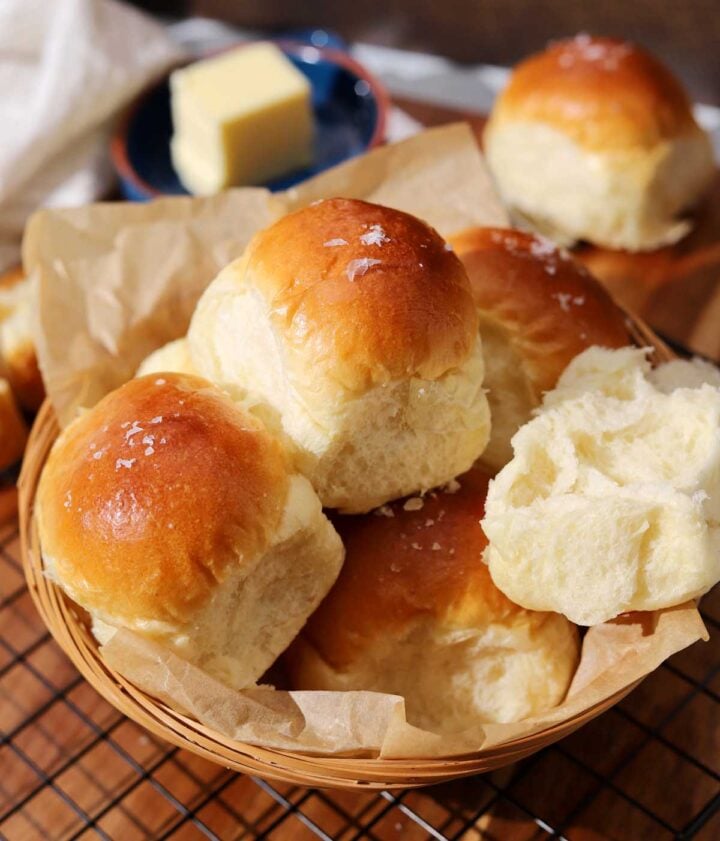 homemade dinner rolls in a basket with parchment paper