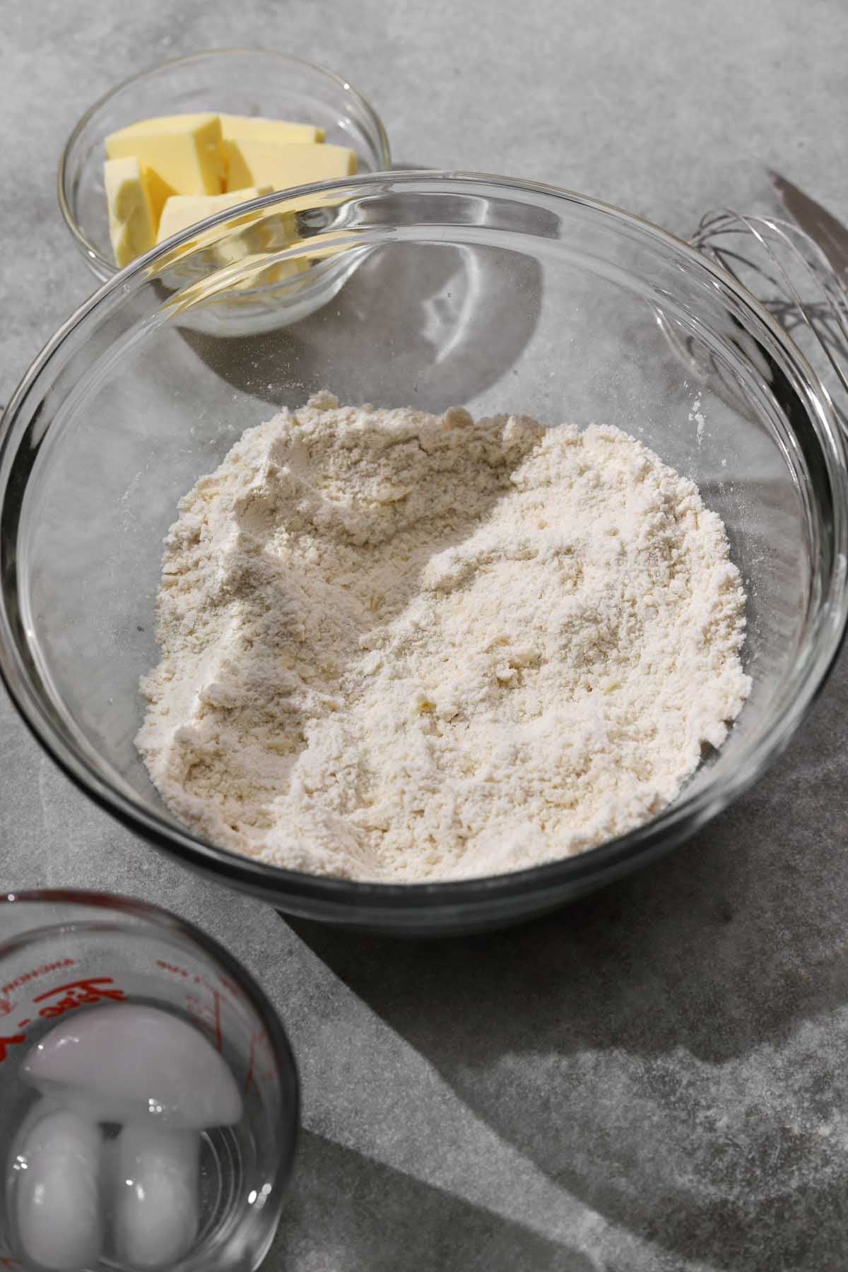 single crust pie dough ingredients in a bowl, rubbing butter into flour before adding water