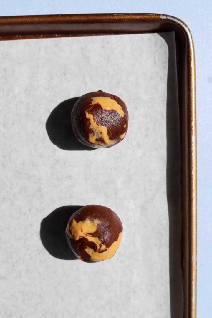 chocolate peanut butter fudge swirl cookie dough balls on parchment-lined baking sheet before baking