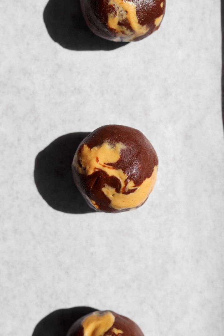 chocolate peanut butter fudge swirl cookie dough balls on parchment-lined baking sheet before baking