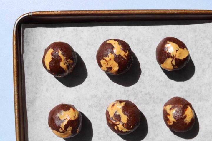 chocolate peanut butter fudge swirl cookie dough balls on parchment-lined baking sheet before baking
