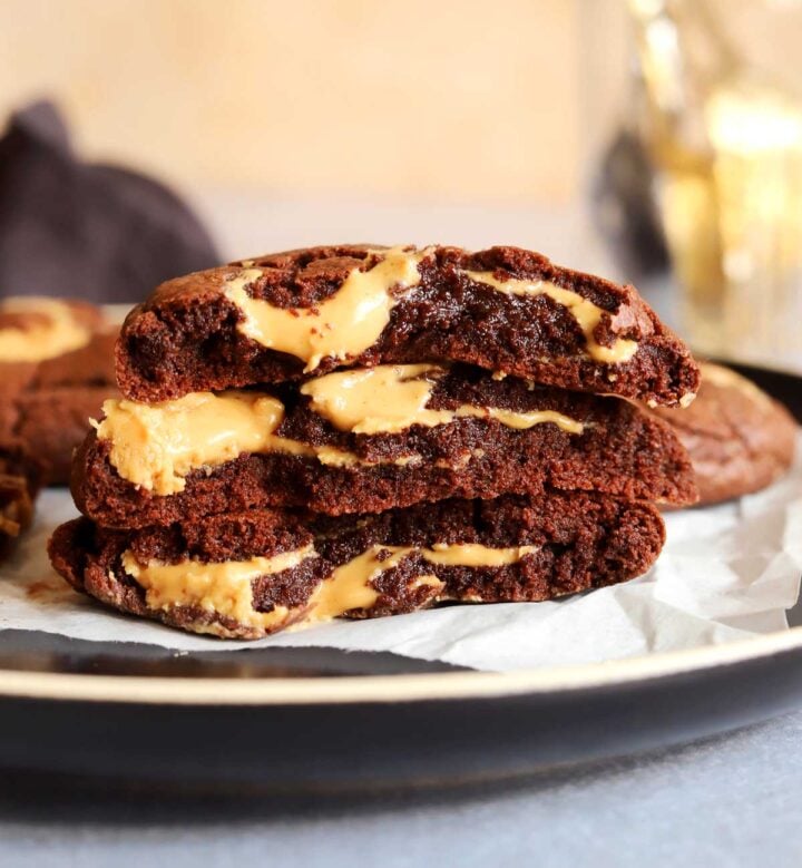 stack of peanut butter fudge swirl cookies broken in half on a plate showing fudgy texture