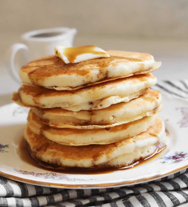 stack of fluffy egg white pancakes on a plate with butter and maple syrup