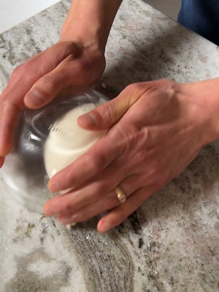 Place the bowl over the ball and make wide circles to pull tension on the dough.