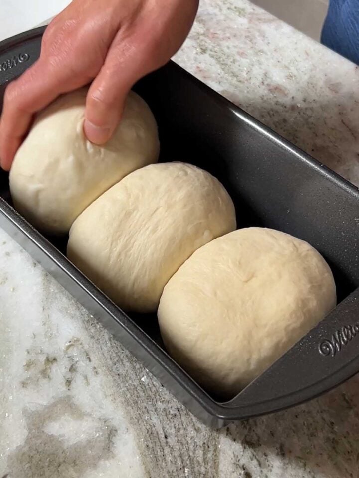 Place dough balls into prepared loaf pan to rise before baking.