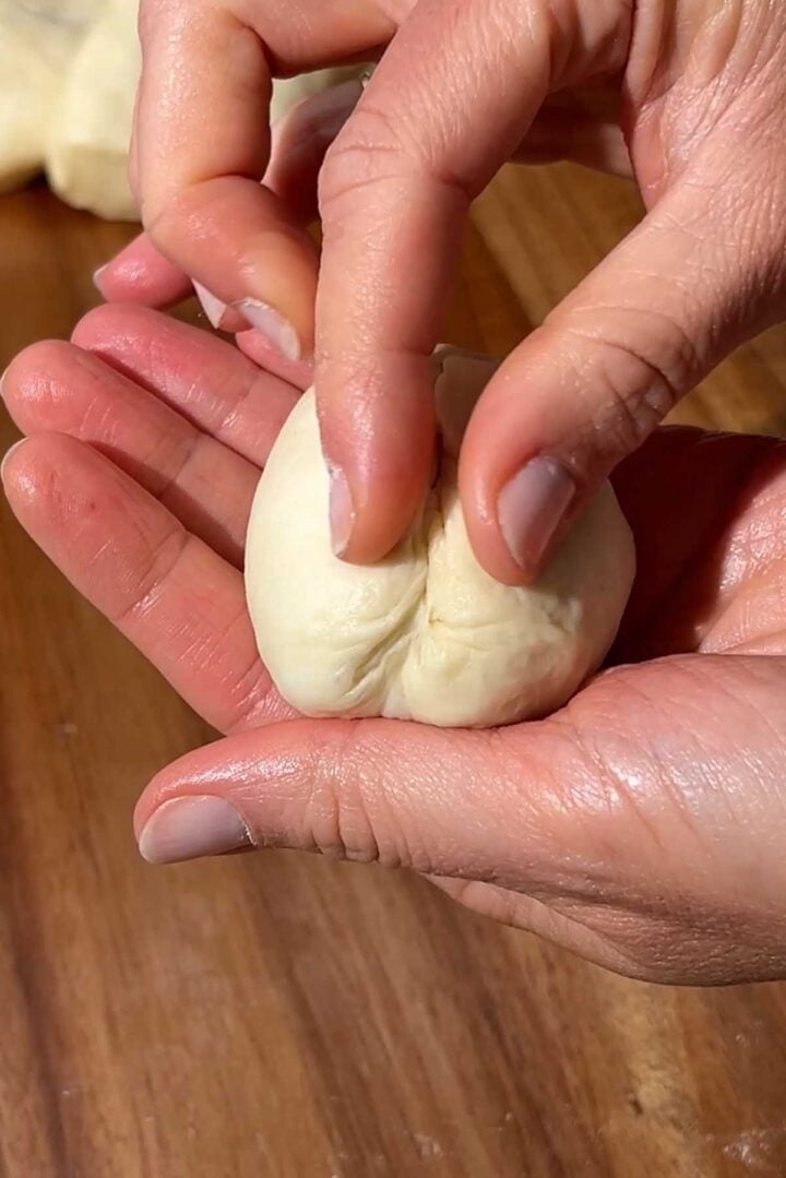 pinch the bottom to seal and pull tension on the dough balls.