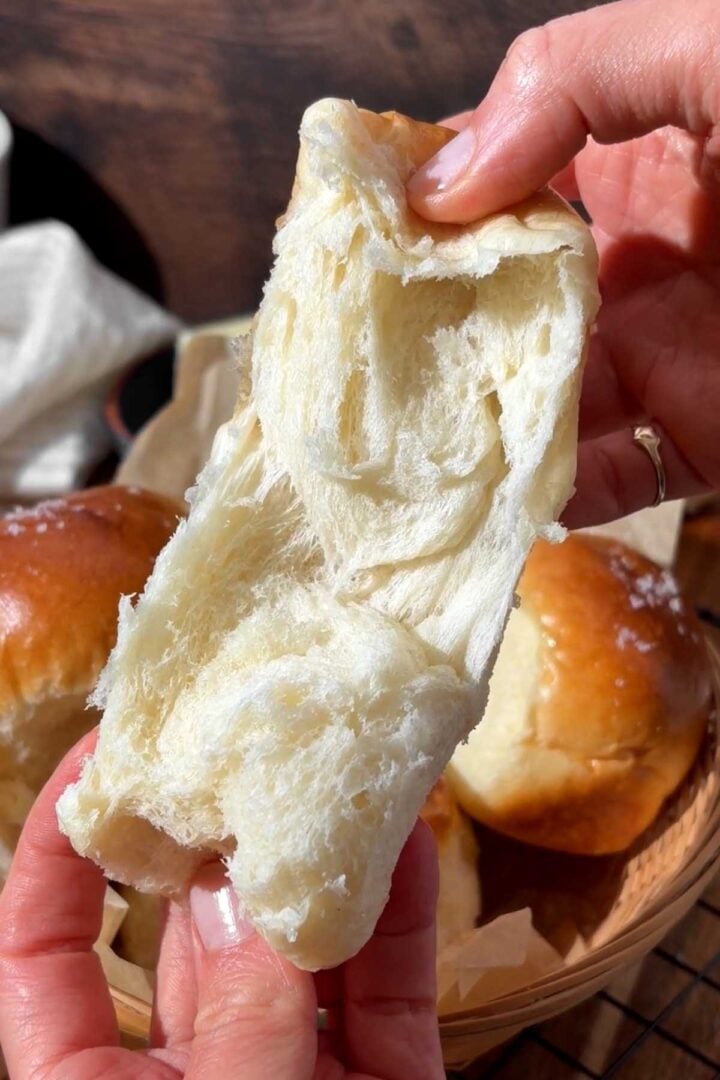Dinner roll torn open showing soft and fluffy interior crumb.